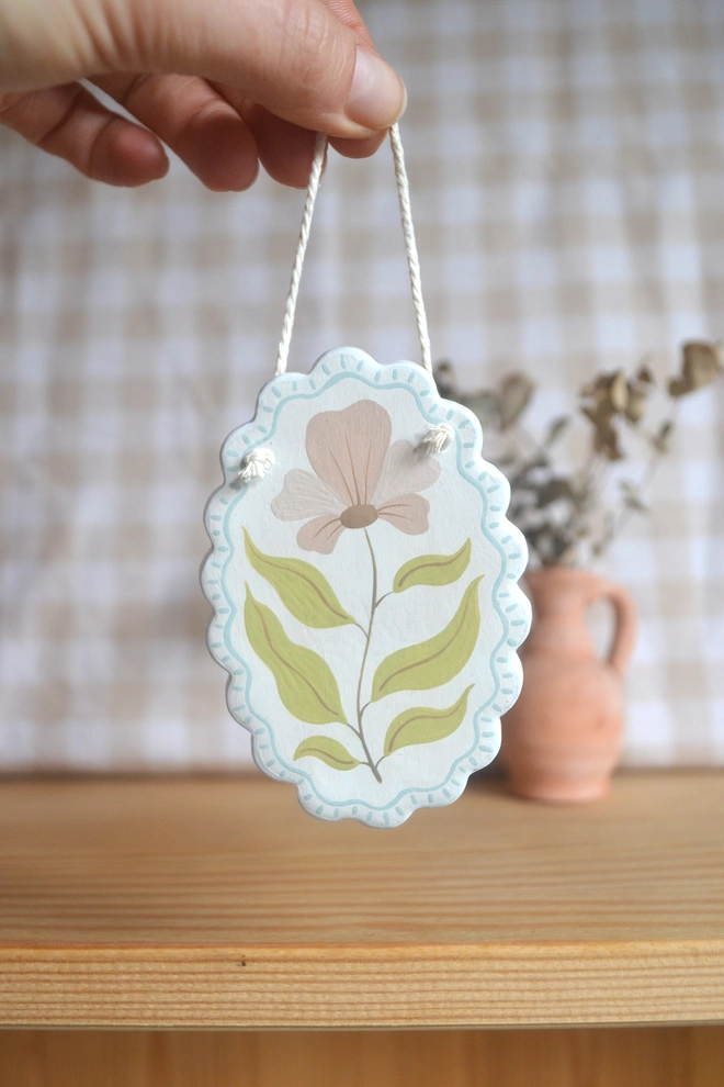 hanging ceramic ornament with blue border and pink an green flower