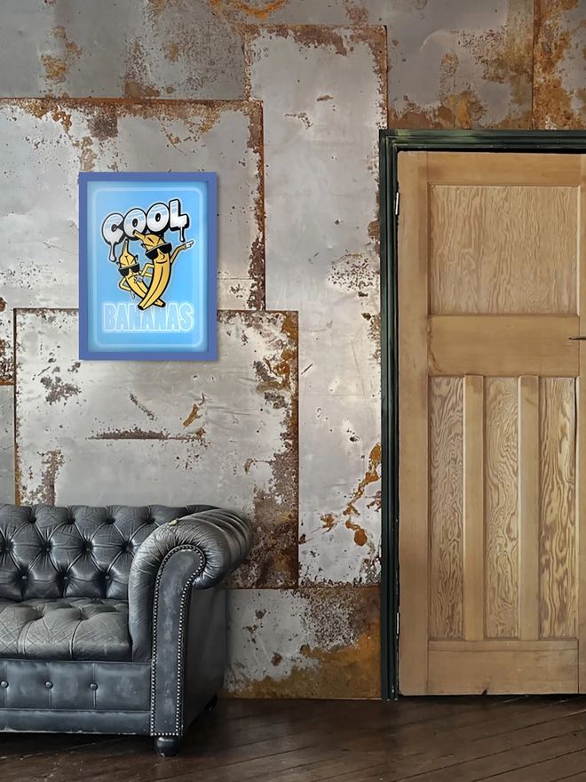 'Cool Bananas' Gold Leaf Glass Artwork, hanging on an metal wall. 