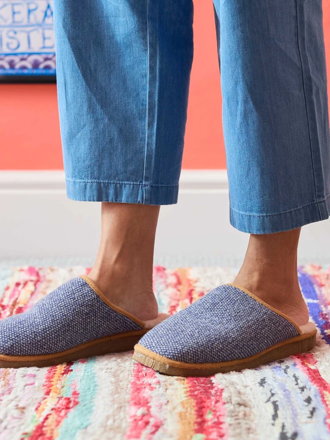 Lambswool & Sheepskin Slippers, a pair of colourful lambswool and sheepskin slippers sitting modelled in front of a colourful wall. 