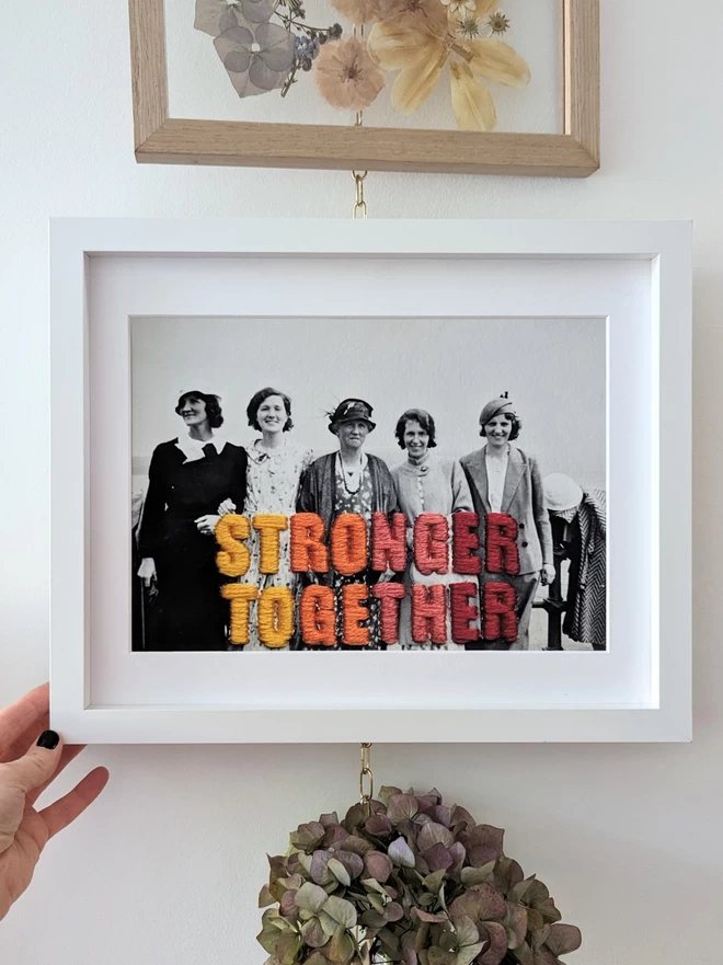 B&W photo, 5 women with Stonger Together embroidery print in frame
