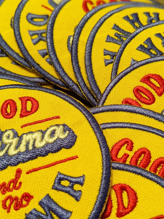 Yellow, Blue & Red round typographic patch reading 'Good Karma and No Drama'. The word Karma is written in a thick cursive lettering style in white, with a blue drop shadow, while the additional type is written in a retro style capital lettering & a smaller red cursive making up a fun retro style fabric patch. 