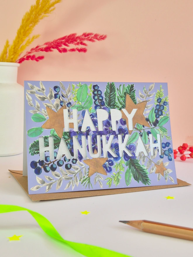 Hanukkah card with blue hydrangea, stars and paper cut text with a metallic silver backing paper 