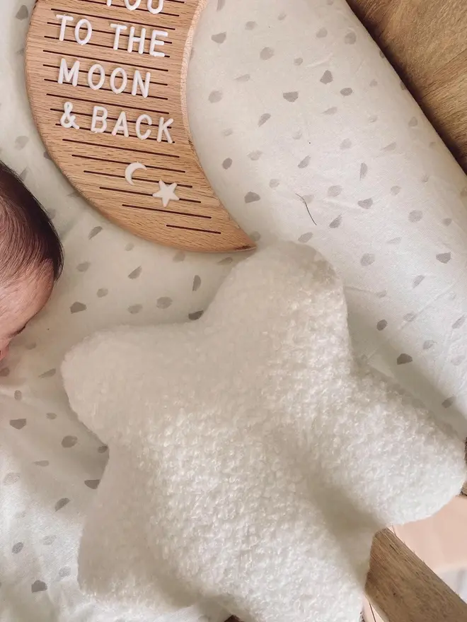 boucle star pillow. a star shaped pillow cushion in a baby's cot.