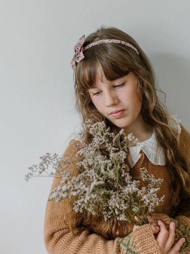 girl with long brown hair flowers and wearing a liberty alice band