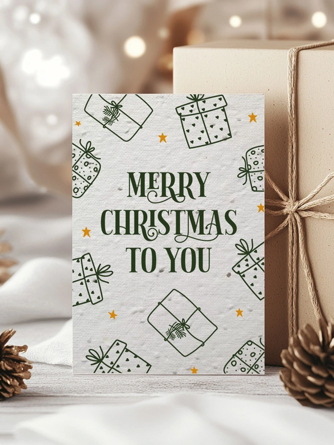 Christmas Card with 'Merry Christmas To You' with presents around the edge of the card. The card is surrounded by presents with gold ribbon