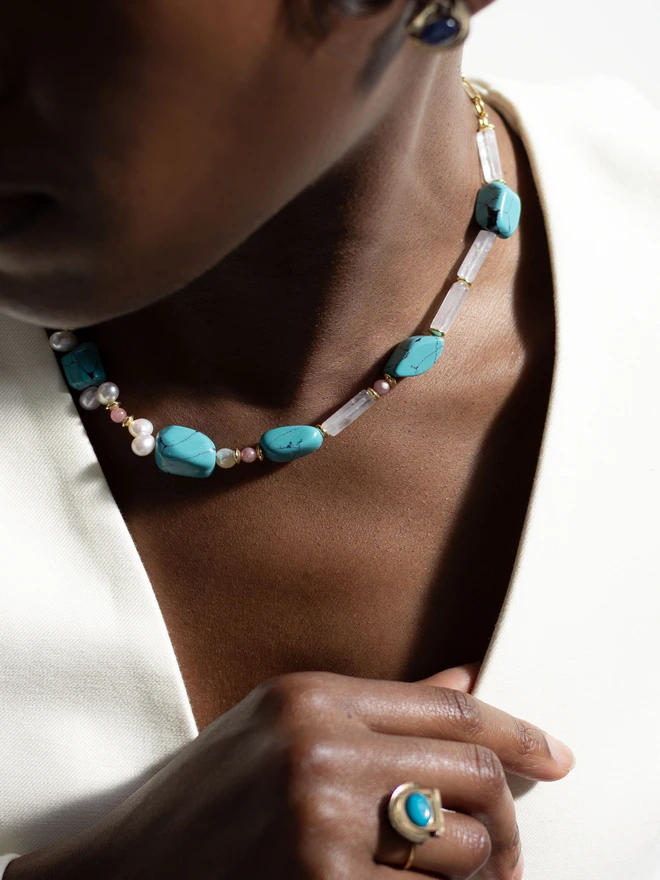 Necklace with turquoise beads and pearls on a person's neck