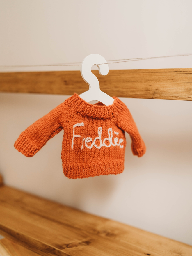 hand knit orange personalised teddy bear jumper on toy hanger