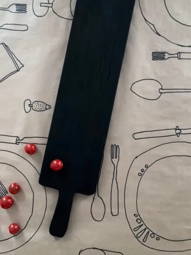 Appetiser board long narrow charred black on hand drawn table setting on brown paper