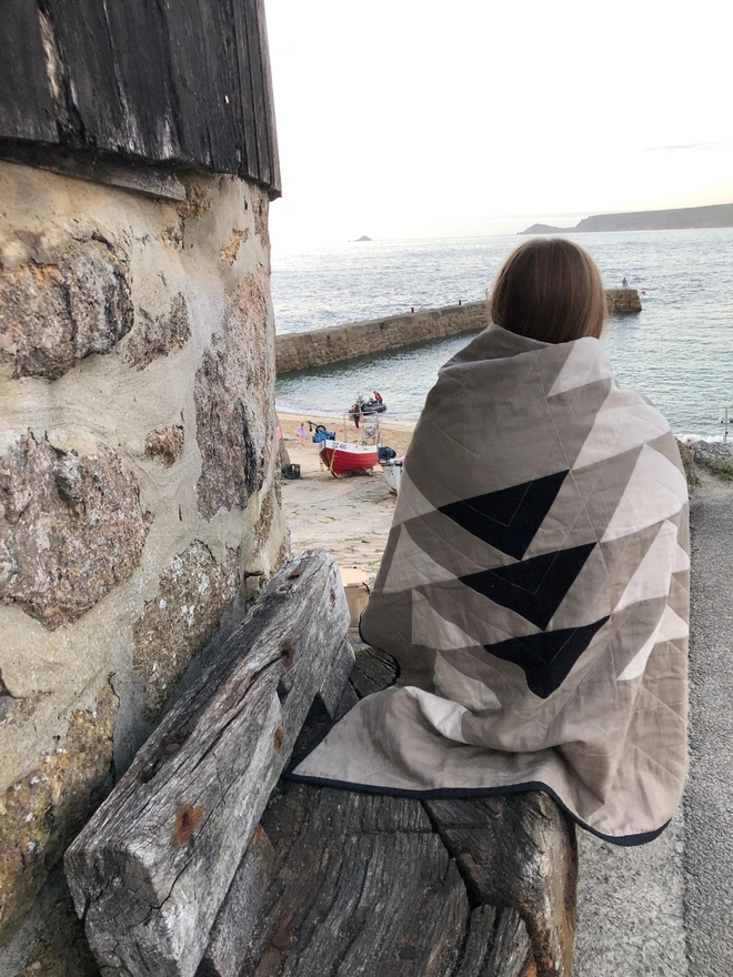 Flow Taupe Throw Quilt used as a blanket to provide an extra layer outside.