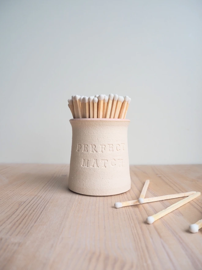 'Perfect Match' match pot with white tip matches inside and some white tip matches lay next to the pot