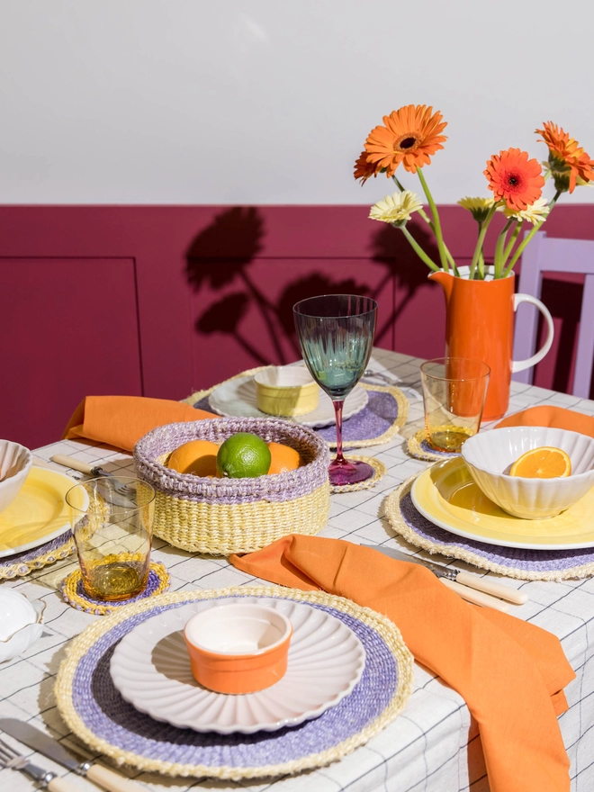 Tablescape of purple and yellow woven tableware