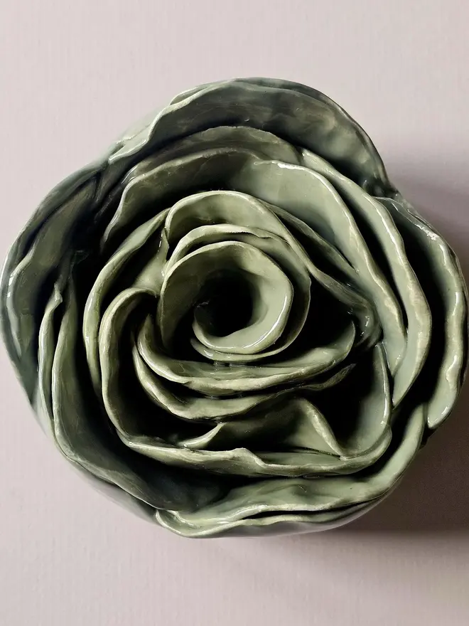 Handmade ceramic rose sculpture with a green glossy glaze, crafted in 3D and designed to hang on a wall