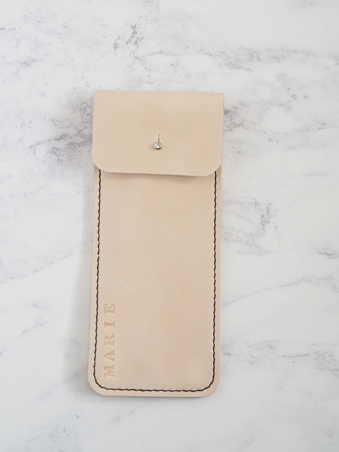 Personalised name leather pencil case. A slim handmade natural cream leather pencil sleeve, personalised with a name along one edge.