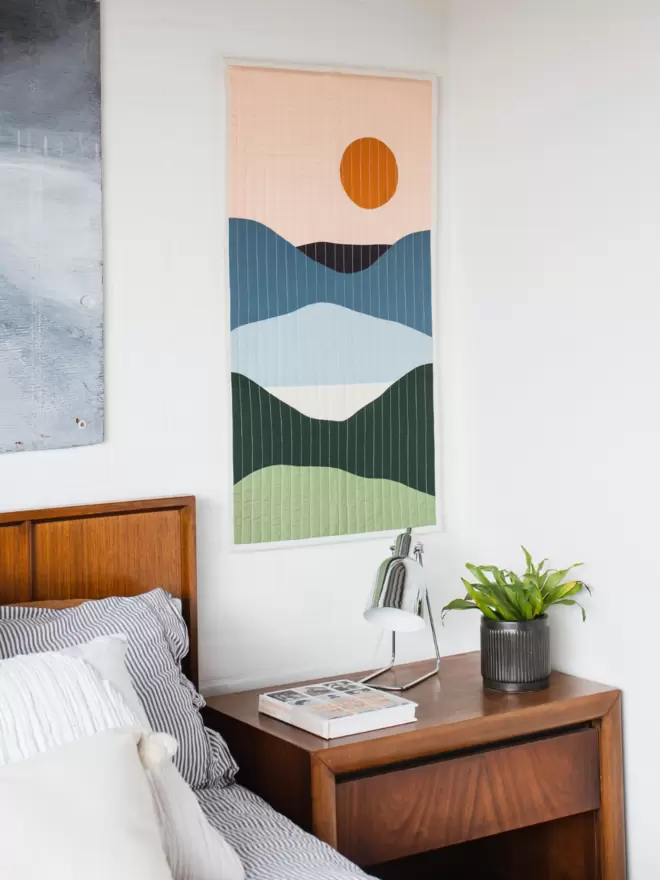Lakeview Quilt Hanging On Wall Above Wooden Furniture In Bedroom