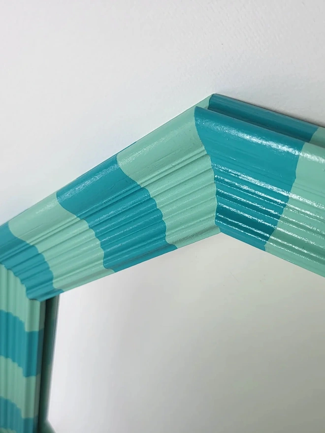 side close up view of hexagon shaped wooden mirror hand painted in mint green