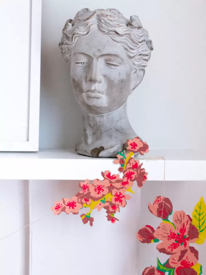 Blossom garland displayed on mantelpiece with grey head bust 
