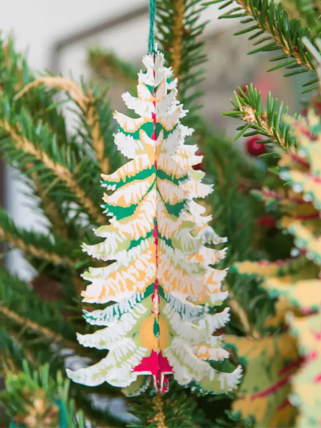 Close-up, detailed shot: green tree paper folded out hanging on christmas tree