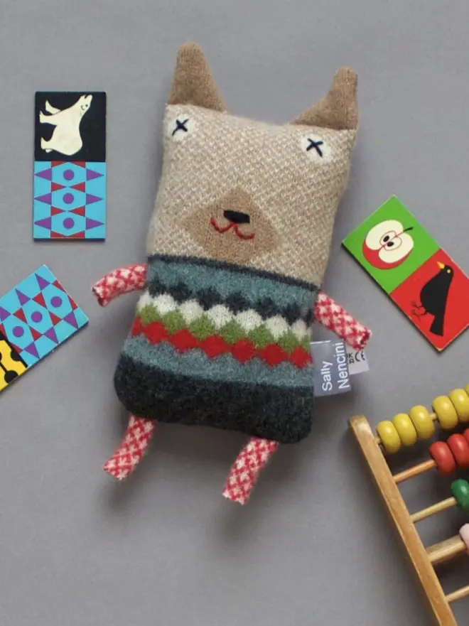 dog plush with diamond pattern jumper surrounded by kids toys