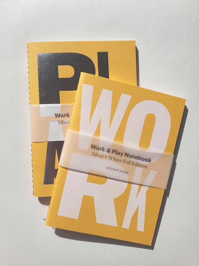 Yellow notebook with the words work and play on the cover