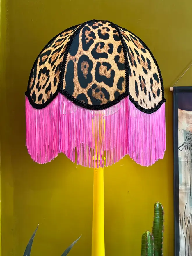 Vintage Fringed Lampshade in Leopardess With Pink Fringe, in a room. 