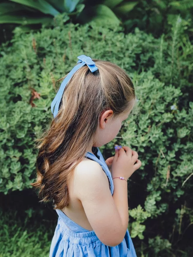 Child standing outside wearing the blue velvet hair bow.