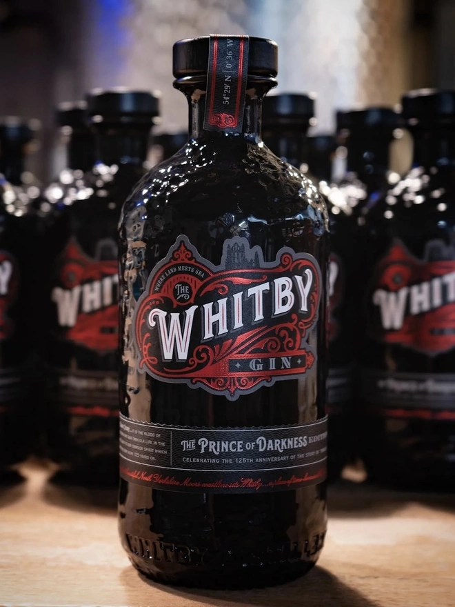 Prince Of Darkness Gin, a group of gin bottles sitting on a wooden surface. 