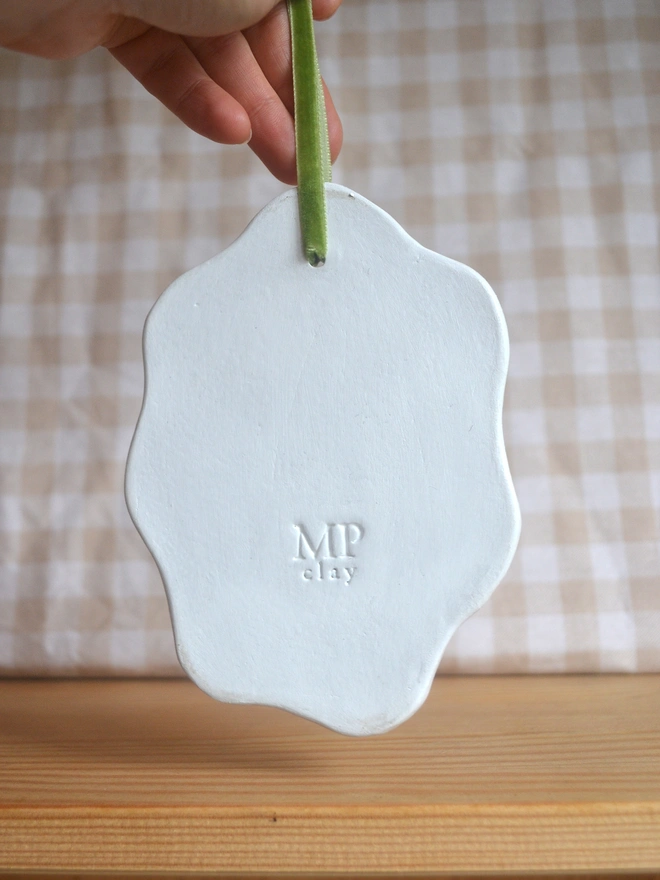 back of hanging clay sign with 'MP' logo stamped into it