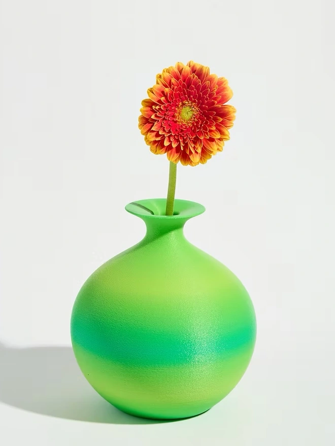 3d printed vase in green stripes with bright pink flower