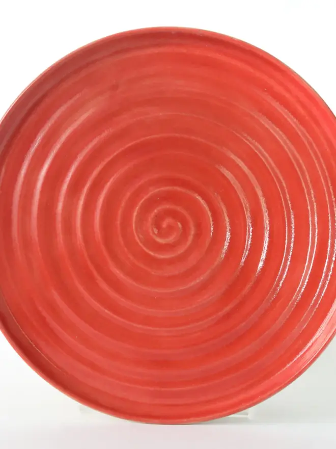 red ceramic plate with textured swirl design