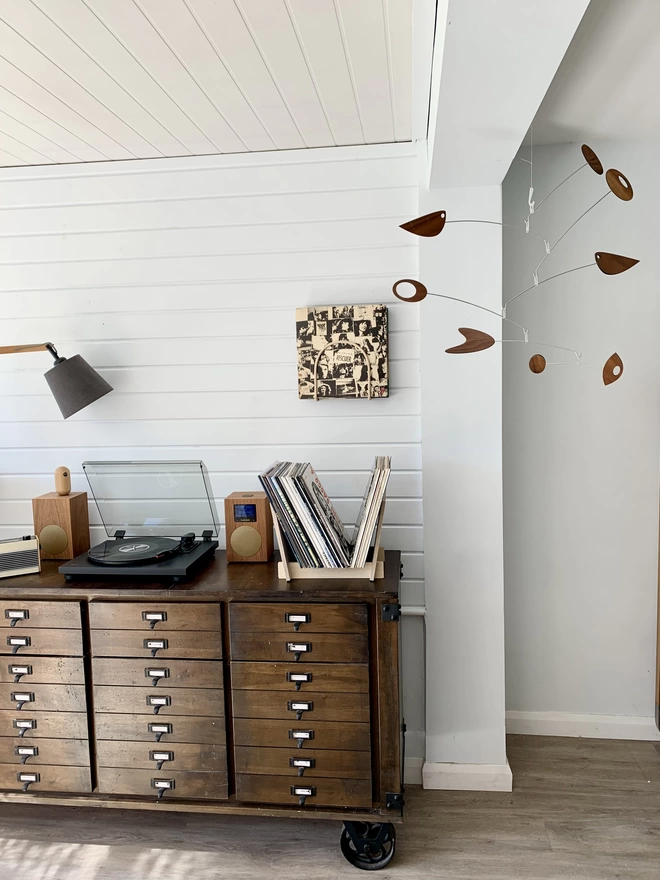 flip side on ontop of sideboard with wooden mobile hanging above