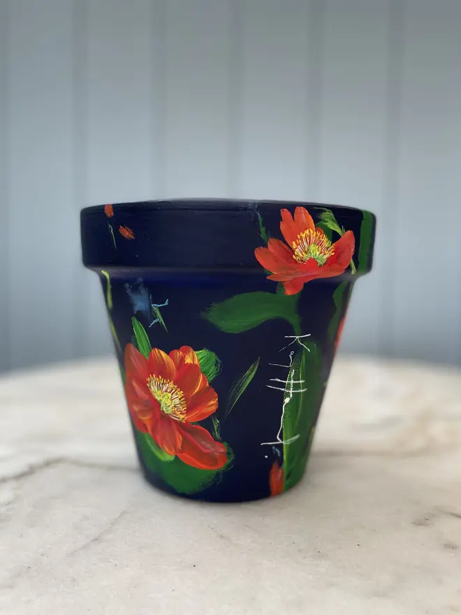 Unique hand-painted terracotta pot featuring orange Icelandic poppies on a deep blue background
