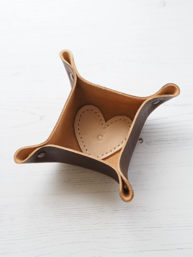 Personalised Leather Tray. A mini square trinket tray in tan brown with a cream love heart stitched the base. Personalised with a single letter in the middle.