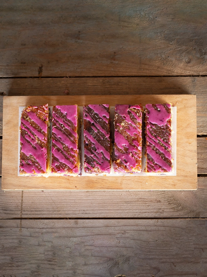Four slices of Lemon and Blueberry cake, showing a drizzle of bright pink icing