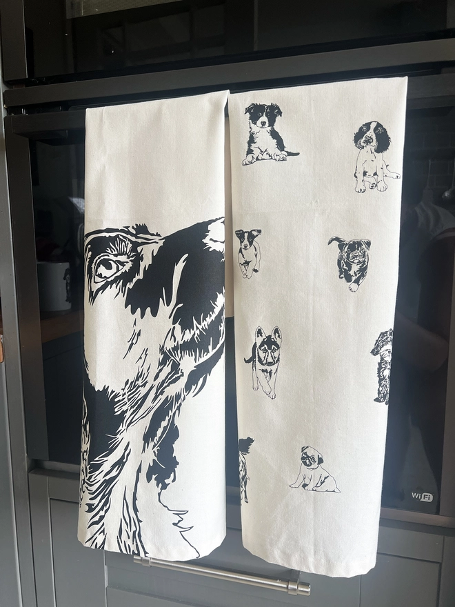 folded puppies tea towel next to a Labrador tea towel on an oven door