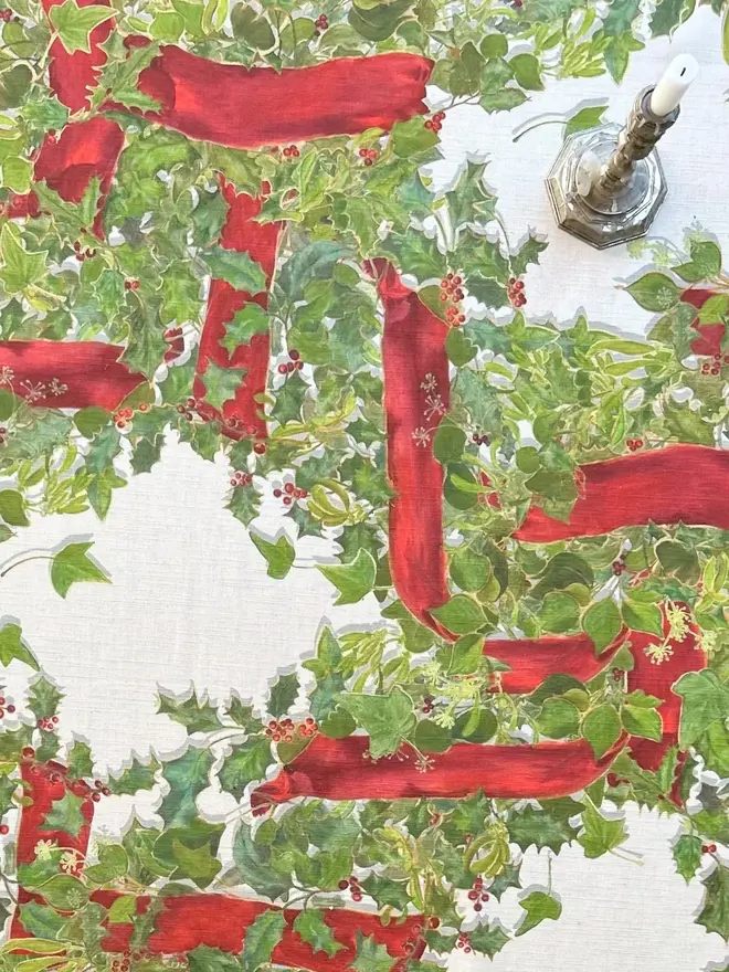 christmas garland lattice tablecloth. a tablecloth printed with holly, ivy and mistletoe on a table.