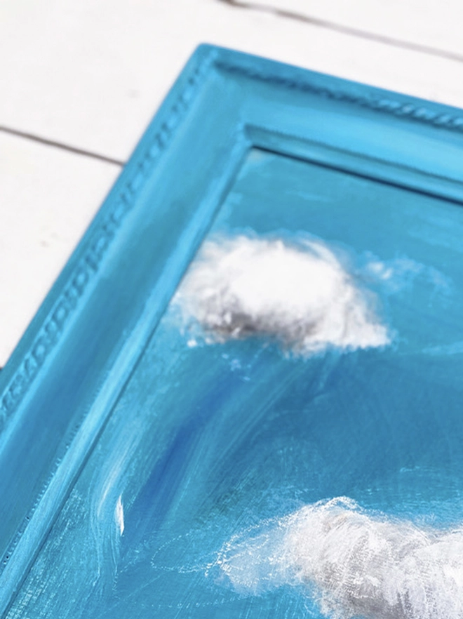 large cloud painting in turquoise painted directly onto a frame