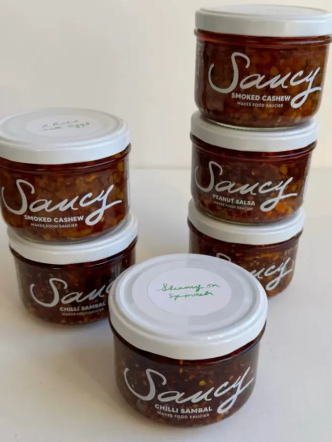 The Extra Saucy Collection (Set Of 6), a collection of 6 sauces sitting on a white table surface against a grey backdrop. 
