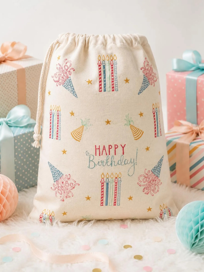 personalised drawstring birthday bag. a drawstring bag with printed candles, streamers and a birthday message.