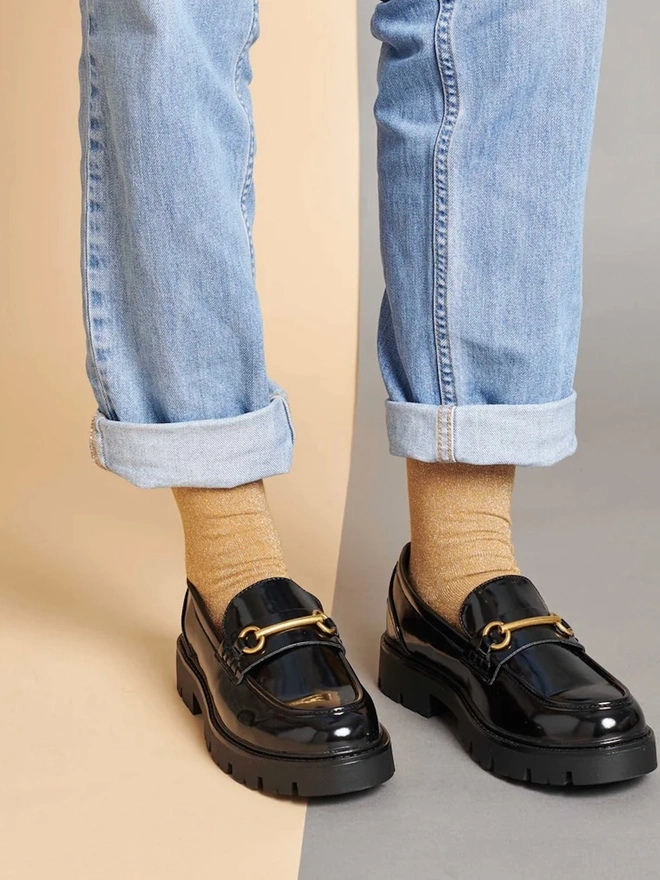 Women's Glitter Organic Cotten Ankle Socks, a woman wearing a pair of colourful patterned socks above a decorated surface. 