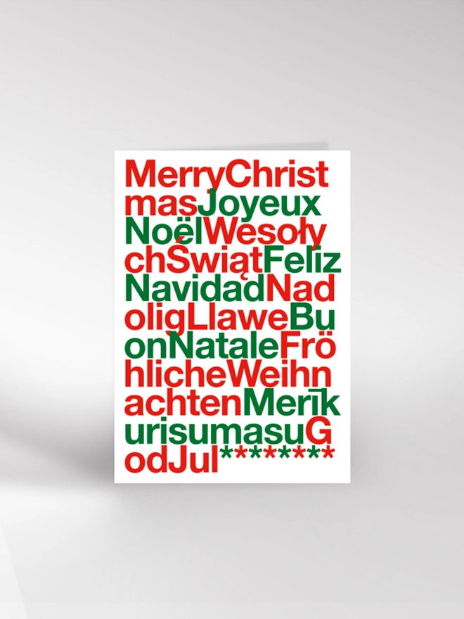 Red, green and white typographic Christmas card saying Merry Christmas in multiple languages 