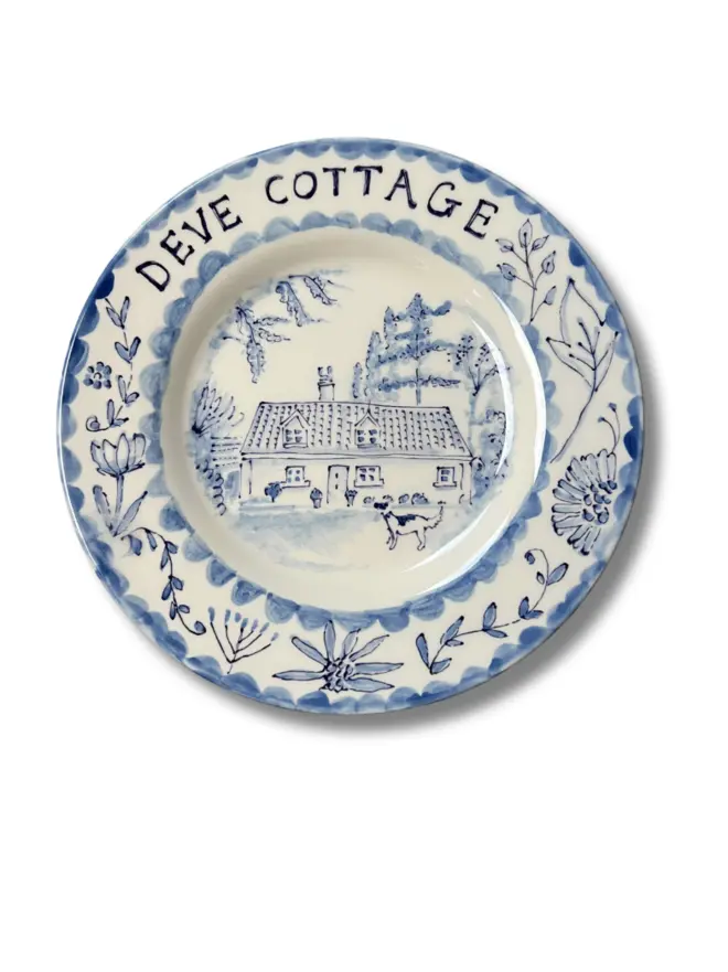Two tone blue scene with name of cottage across the top of the plate, and the cottage itself set within. replete with botanical border 