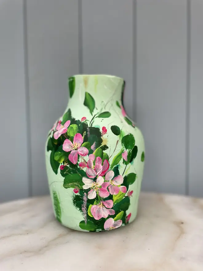 hand painted terracotta floral dried flowers vase pale green background with pink and white apple blossom flowers.