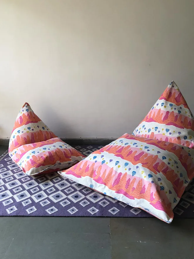Fairy Chimney Bean Bag Cover, a pink and orange bean bag sitting on a decorated floor. 