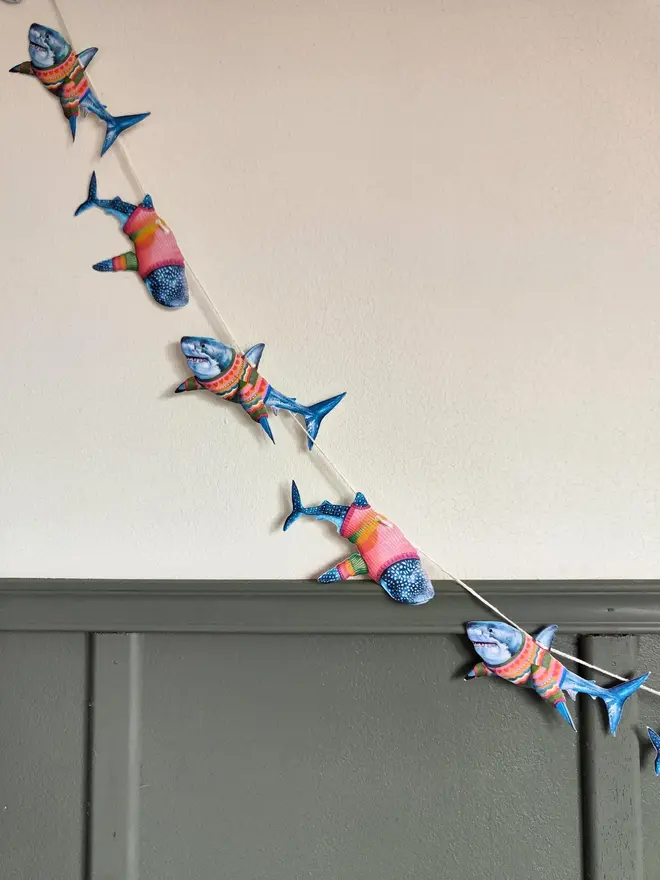 illustrated shark garland. sharks in jumpers on bunting hanging on wall