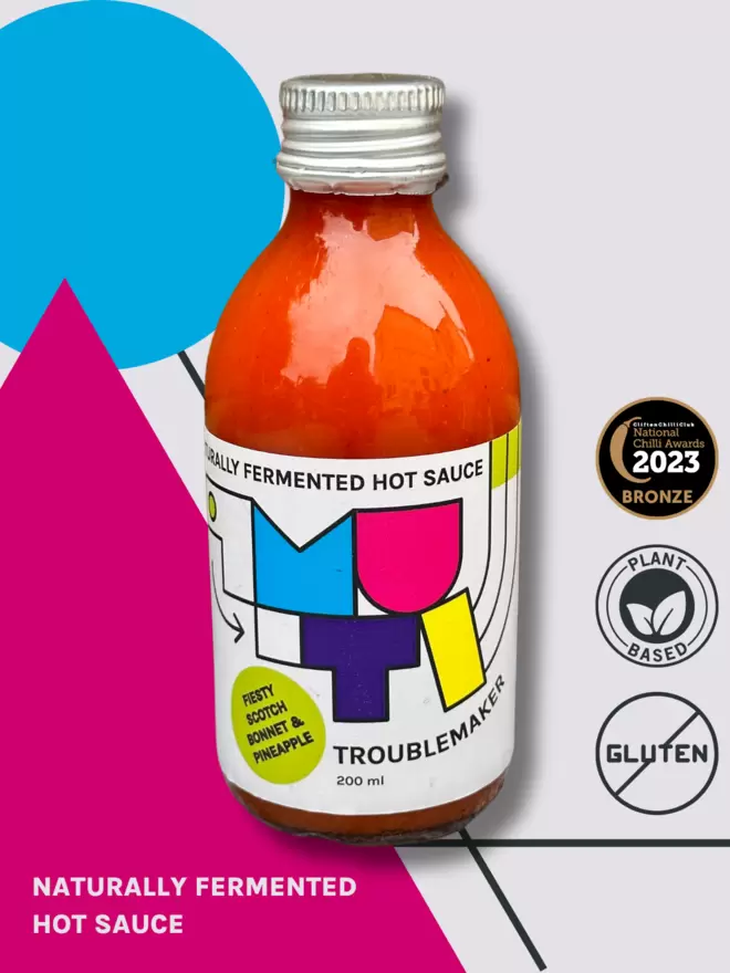 Picture of Muti Troublemaker on a colourful pop art back ground with icons stating "Plant Based", "Bronze Award National Chilli Awards 2023", "no Gluten", and "Microbes for the masses".