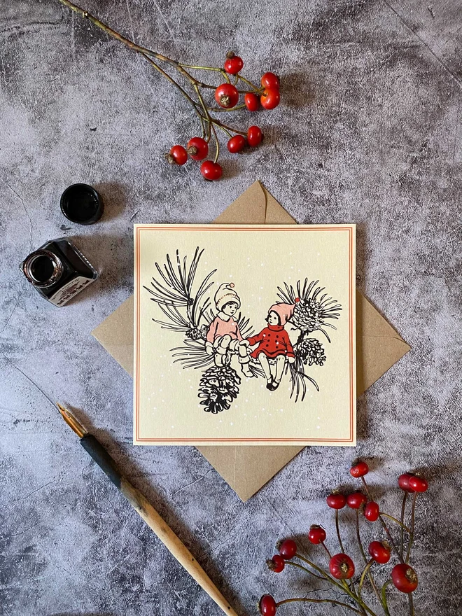 a vintage style christmas card featuring 2 children sat on a pinecone branch