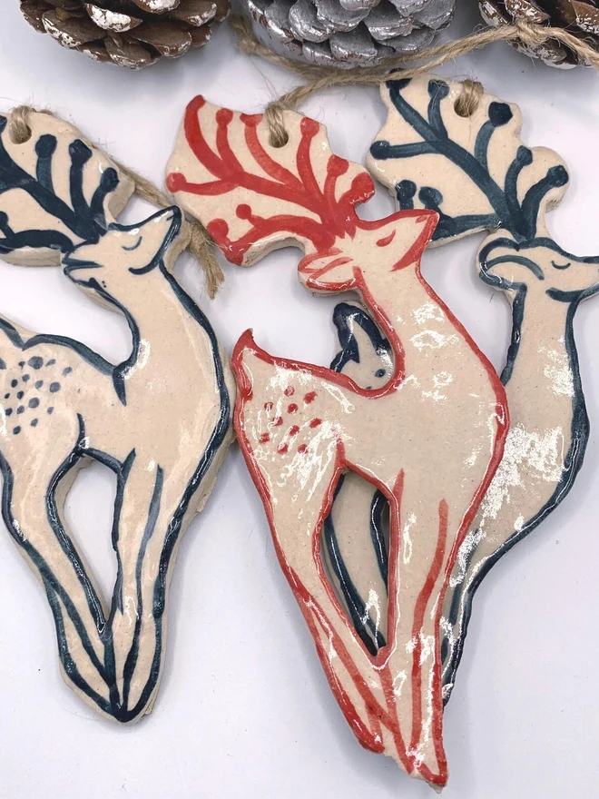 Handmade Ceramic Reindeer Ornament Scandinavian Folk Decor, a group of colourful reindeer decorations sitting on a plain white surface. 