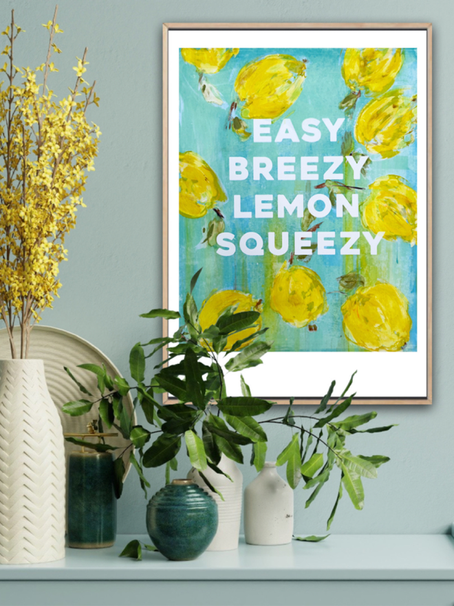 EASY BREEZY LEMON SQUEEZY fine art print shown in a room with a light sage background and a botanical floral arrangement.  Art by M.E. Ster-Molnar 