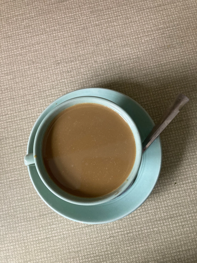 A pale green 1940s cup and saucer from the company Beryl Ware. The cup is filled to the brim with resin ‘tea’. There is a tea spoon in the saucer which has a drop of resin tea in its bowl.