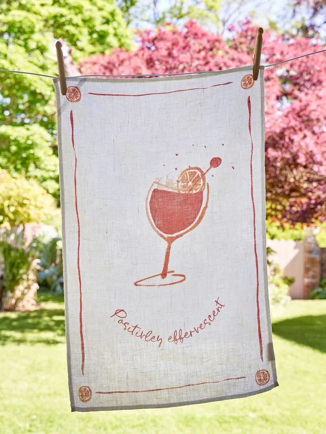 Positively Effervescent - Aperol Spritz Linen Tea Towel, Hanging on the washing line in the garden 